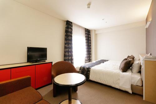 a hotel room with a bed and a tv at The Celecton Fukushima in Fukushima