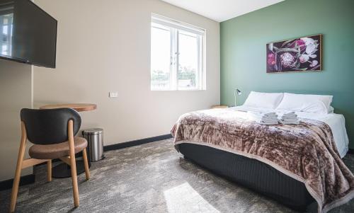 a bedroom with a bed and a chair and a window at The Peakhurst in Peakhurst
