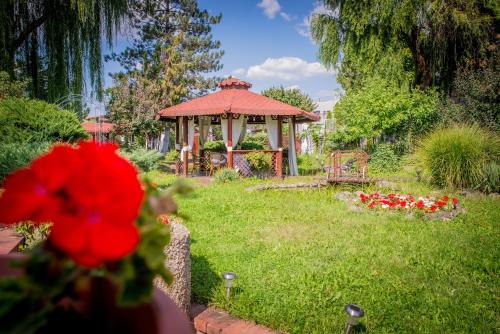 a garden with a gazebo and a red flower at Hotel Senator in Timişoara