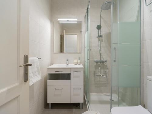 Un baño blanco con ducha y lavabo. en HomeForGuest Modern Apartment in San Agustin 2 min from the beach, en San Bartolomé