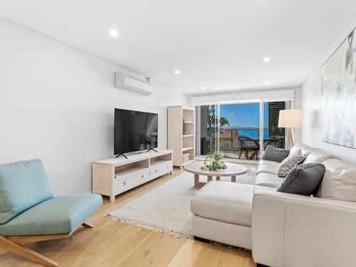a living room with a white couch and a tv at The Shoal Apartments Unit 306 6 Bullecourt in Shoal Bay