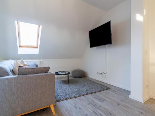 a living room with a couch and a tv on a wall at Limehome Chemnitz Hartmannstraße in Chemnitz