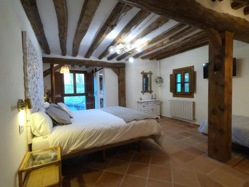 a bedroom with a large bed in a room with wooden ceilings at Molino del Corregidor in San Román de Cameros
