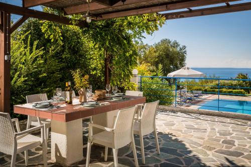 a table and chairs on a patio with a view of the ocean at Villa Rudi in Trapezaki