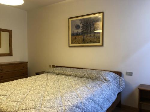 een slaapkamer met een bed en een foto aan de muur bij 017 Trilocale, Pinzolo in Pinzolo