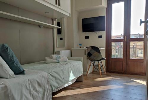 a bedroom with a bed and a tv and a chair at La Locanda del Bistrot dei Vinai in Cuneo