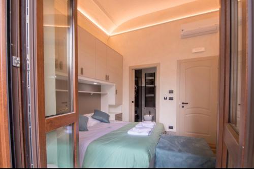 a bedroom with a bed with green sheets and a mirror at La Locanda del Bistrot dei Vinai in Cuneo
