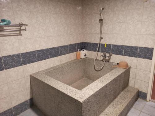 La salle de bains est pourvue d'une baignoire et d'une douche. dans l'établissement 九族飯店 臺東縣旅館004號, à Wenquan