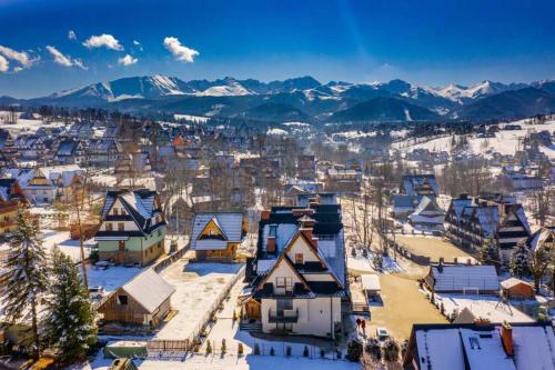 eine schneebedeckte Stadt mit Bergen im Hintergrund in der Unterkunft Willa Tatra in Zakopane
