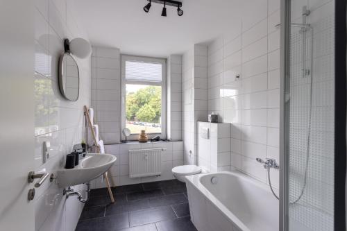 a white bathroom with a tub and a sink at Limehome Chemnitz Hartmannstraße in Chemnitz