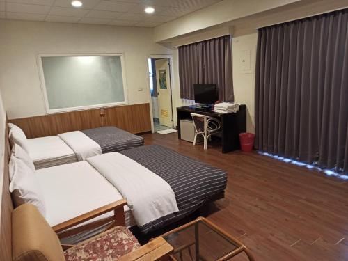 um quarto de hospital com duas camas e uma secretária em 九族飯店 臺東縣旅館004號 em Wenquan
