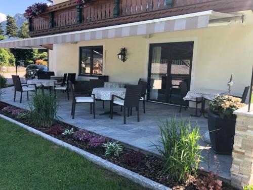 a patio with tables and chairs and a balcony at Gästehaus Kloibergütl in Sankt Gilgen