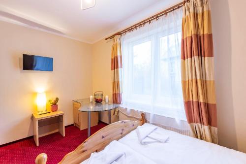 a bedroom with a bed and a table and a window at VacationClub – 300 Mill Apartament 1 in Szklarska Poręba