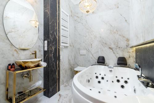 a bathroom with a white tub and a mirror at Kazimierz Studio with Jacuzzi by Renters Prestige in Kraków
