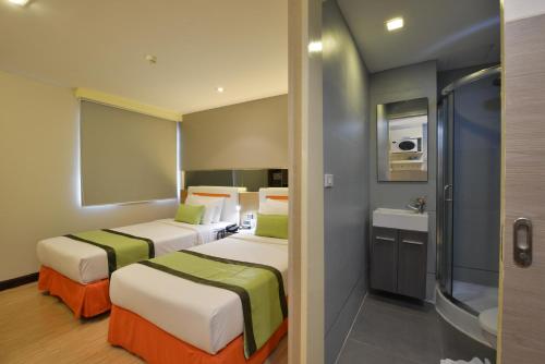 2 Betten in einem Hotelzimmer mit Bad in der Unterkunft Arawana Express Phromphong in Bangkok