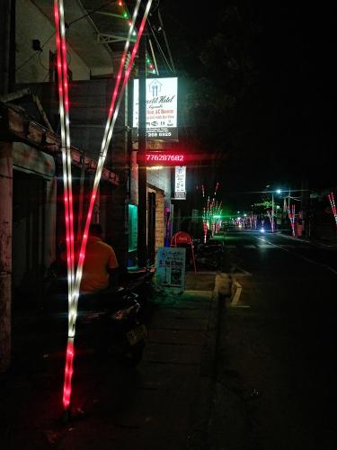 a person sitting outside of a building at night at Le Petit Hotel & Restaurant in Negombo