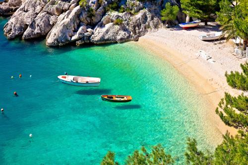 two boats in the water next to a beach at Bluesun hotel Berulia in Brela