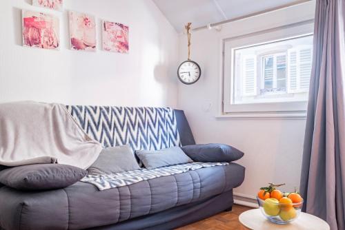 un salon avec un canapé et une horloge au mur dans l'établissement Gîte Le Colombier Sélestat - 30min EuropaPark, à Sélestat