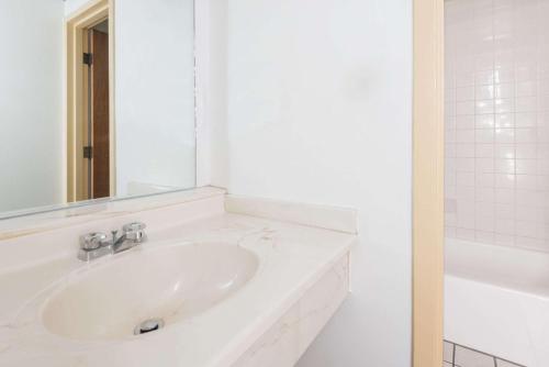 a white bathroom with a sink and a mirror at Super 8 by Wyndham Laramie in Laramie