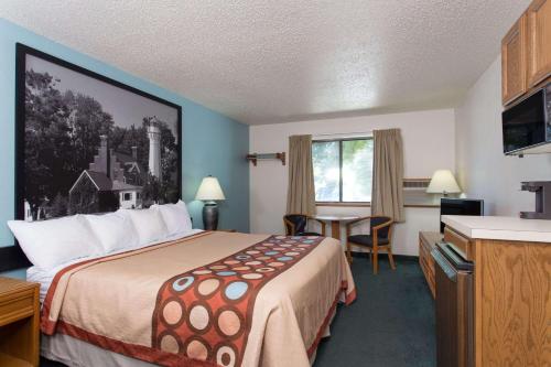 a hotel room with a bed and a table at Super 8 by Wyndham Houghton Lake in Houghton Lake