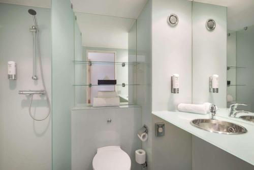 a bathroom with a toilet and a sink and a shower at Ramada by Wyndham Belfast in Belfast