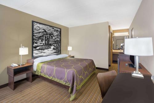 a hotel room with a bed and a desk at Super 8 by Wyndham Knoxville North/Powell in Knoxville
