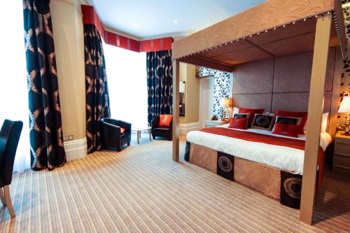 een hotelkamer met een groot bed met een baldakijn bij Best Western York House Hotel in Eastbourne