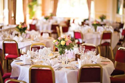 a room full of tables with white table cloths and flowers at Best Western York House Hotel in Eastbourne