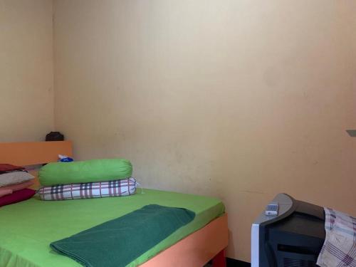 ein Schlafzimmer mit einem grünen Bett und einem TV in der Unterkunft OYO 90770 Wisma Rima Melati in Tolo