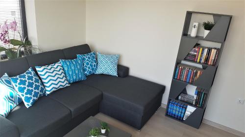 een woonkamer met een bank met kussens en een boekenplank bij Azzurro-Top floor apartment in quiet neighborhood, Free private parking in Varna