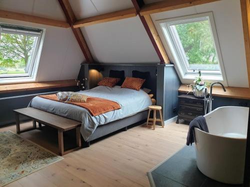 um quarto com uma cama, 2 janelas e uma banheira em B&B Het Nijenhuis em Diffelen