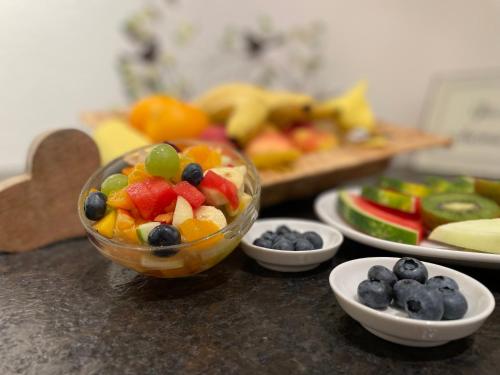 a bowl of fruit on a counter with plates of fruit at Aparthotel Grabner in Bad Füssing