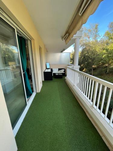 een balkon met groene vloerbedekking op een huis bij Résidence standing Rivièra Golf Mandelieu in Mandelieu-la-Napoule