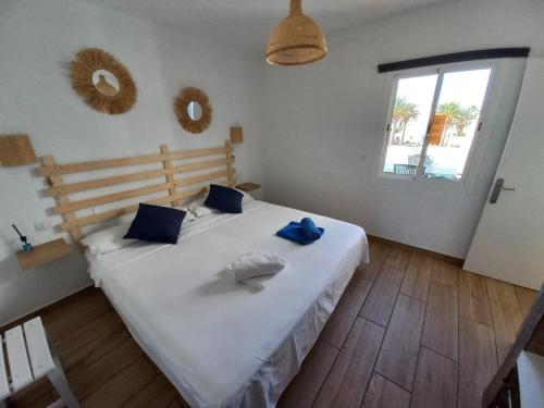 a bedroom with a large white bed with blue pillows at Apartamento recien reformado en centro a tres minutos de la playa in Corralejo