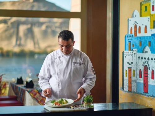 a chef preparing a plate of food on a counter at Mövenpick Resort Aswan in Aswan