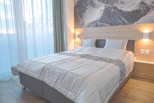 a bedroom with a large bed with a mountain painting on the wall at TATRYSTAY Apartment Sankt Bernard in Nový Smokovec