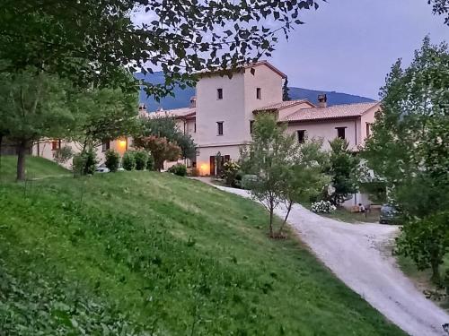 a house on a grassy hill with a dirt road at Agriturismo Il Covo del Solengo in Valtopina