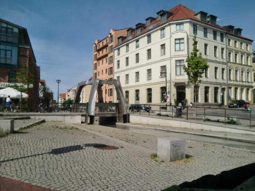 a city with buildings and a statue in the street at Ferienwohnungen Am Schwanenteich in Rostock