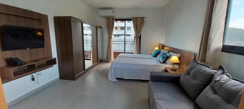 a hotel room with a bed and a couch at Vida Studios in Palhoça
