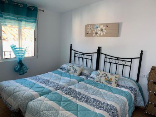 Schlafzimmer mit einem Bett mit einer blauen und weißen Bettdecke in der Unterkunft casita valdivia in Gaucín