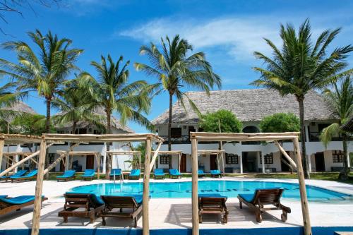 a resort pool with chairs and palm trees at Nest Style Beach Hotel Zanzibar in Makunduchi