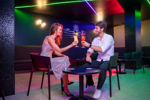 a man and woman sitting at a table with drinks at Hotel Rosamar in Benidorm