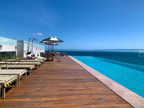 a wooden boardwalk with a pool and tables and an umbrella at Lar Expresso 2222 in Salvador