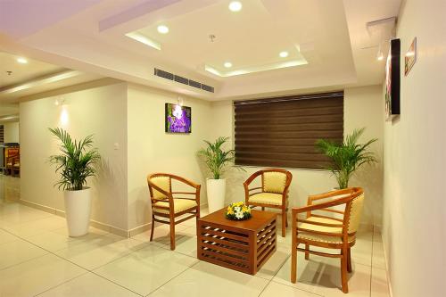 a living room with two chairs and a table with plants at Lumbini Supreme in Trichūr
