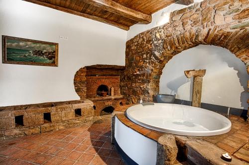 - une grande salle de bains avec une baignoire dans un mur en pierre dans l'établissement Dimora storica Giorni resort & spa, à Pignola