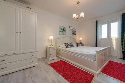 a bedroom with a white bed and a red rug at Villa Tatijana ZadarVillas in Kukljica