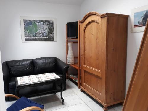 a living room with a leather couch and a cabinet at Kleines Häuschen in Ober-Ramstadt