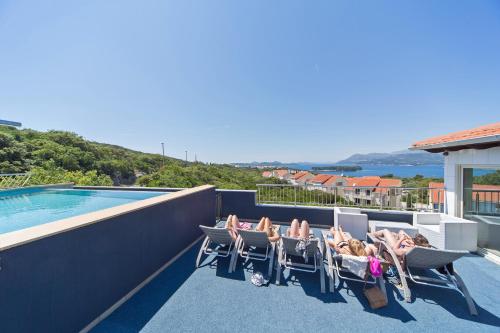 een groep mensen die in stoelen zitten op een balkon met een zwembad bij Villa Antea Apartments in Dubrovnik