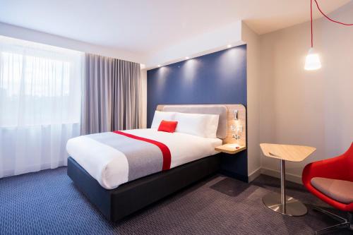 a hotel room with a bed and a red chair at Holiday Inn Express Dublin City Centre by IHG in Dublin