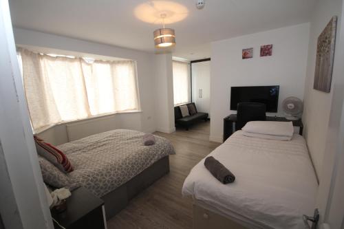 a bedroom with two beds and a television in it at Lee's House in Uxbridge